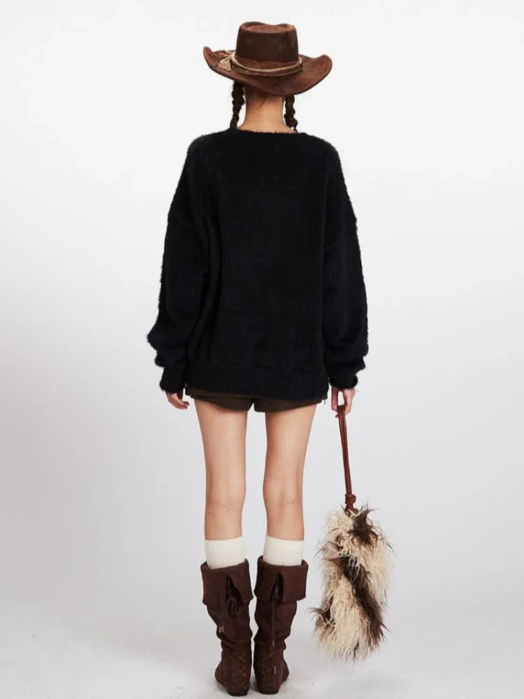 Woman wearing a black fuzzy knit sweater with a brown and white horse graphic on the front, paired with a brown cowboy hat, olive green shorts, white socks, and brown boots.