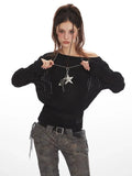 Woman adjusting the neckline of a black off-the-shoulder knit sweater.