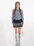 Woman wearing a blue and white plaid button-down shirt with a dark navy ruffled skirt and a plaid mini skirt