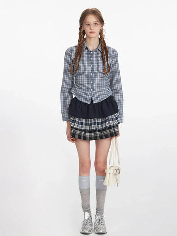 Woman wearing a blue and white plaid button-down shirt with a dark navy ruffled skirt and a plaid mini skirt