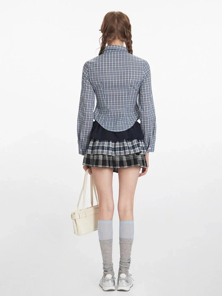 Woman wearing a blue and white plaid button-down shirt with a dark navy ruffled skirt and a plaid mini skirt