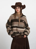Woman posing in a striped knit sweater, brown skirt, and cowboy hat