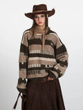 Close-up of a woman wearing a striped knit sweater with a scarf and cowboy hat