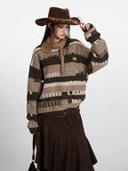 Woman adjusting her cowboy hat while wearing a striped knit sweater