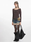 Full-body shot of a woman styled in a striped top, denim skirt, and accessories