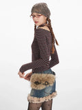 Side profile of a woman wearing a striped off-the-shoulder top and denim skirt
