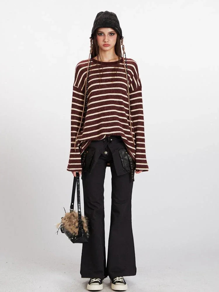 Woman wearing a maroon and cream striped long-sleeve knit sweater with a relaxed fit, black pants, and a black beanie.
