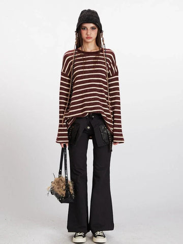 Woman wearing a maroon and cream striped long-sleeve knit sweater with a relaxed fit, black pants, and a black beanie.
