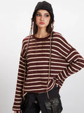 Portrait of a woman wearing a maroon and cream striped knit sweater and a black beanie, with decorative braids.