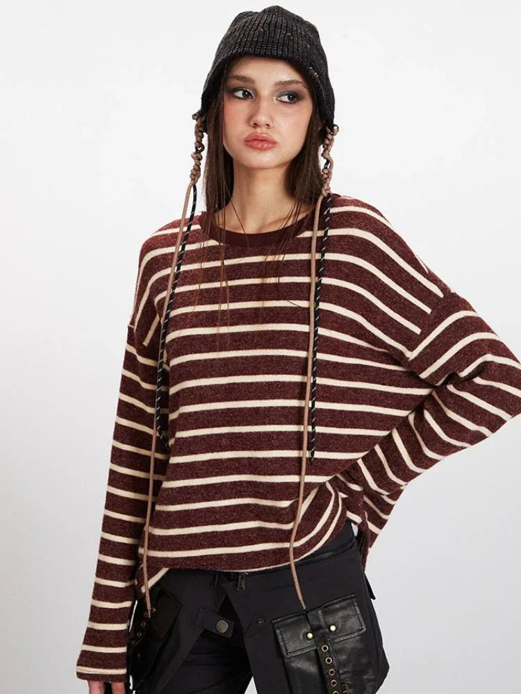 Portrait of a woman wearing a maroon and cream striped knit sweater and a black beanie, with decorative braids.