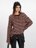 Close-up of a woman's upper body wearing a maroon and cream striped knit sweater, showcasing the relaxed fit and texture.