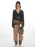 Woman wearing a dark gray long-sleeve v-neck top with a leopard print and faux fur scarf accessory, and tan wide-leg pants.