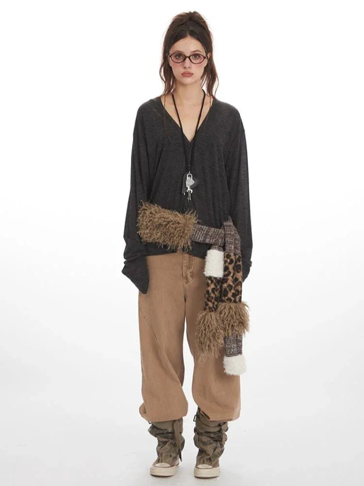 Woman wearing a dark gray long-sleeve v-neck top with a leopard print and faux fur scarf accessory, and tan wide-leg pants.