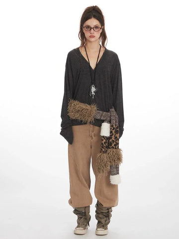 Woman wearing a dark gray long-sleeve v-neck top with a leopard print and faux fur scarf accessory, and tan wide-leg pants.