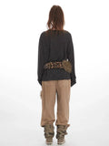 Back view of a woman wearing a dark gray long-sleeve v-neck top with a leopard print and faux fur scarf accessory, and tan wide-leg pants.