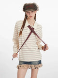 Woman holding the ends of a dark red polka dot tie worn with a cream and dark stripe long sleeve polo shirt and a denim mini skirt with fur trim.