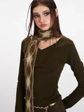 Front view of a woman wearing a long sleeve olive green top and a patterned scarf, styled with a gold chain belt.