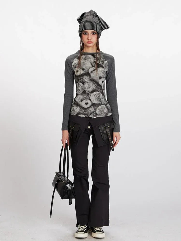 Woman wearing a grey long-sleeve top with a teddy bear print on the front and black pants.