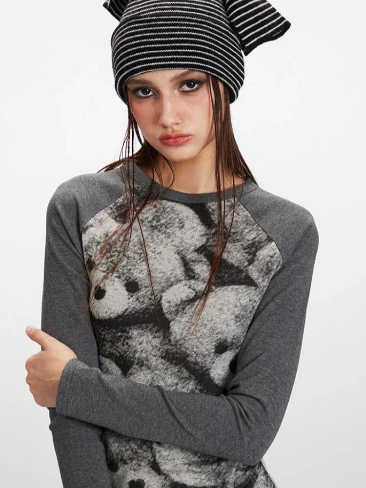 Detailed view of the teddy bear print on the grey long-sleeve top.