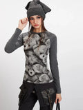 Woman adjusting her beanie while wearing a grey long-sleeve top with a teddy bear print.