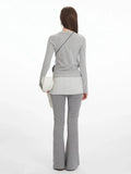 Back view of a model in a grey long-sleeve top and grey flared pants.