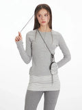 Close-up of the model's face and upper body, showing the grey long-sleeve top with button detail and striped accent.