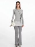 Model wearing a grey long-sleeve top with a button placket and striped hem, paired with grey flared pants.