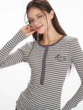 Detailed view of the embroidered emblem on the chest of a grey and white striped long-sleeve top.
