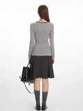 Back view of a woman wearing a grey and white striped long-sleeve top with a button-up placket.