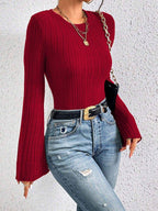 Close-up of a woman's torso wearing a red ribbed knit top with flared sleeves.