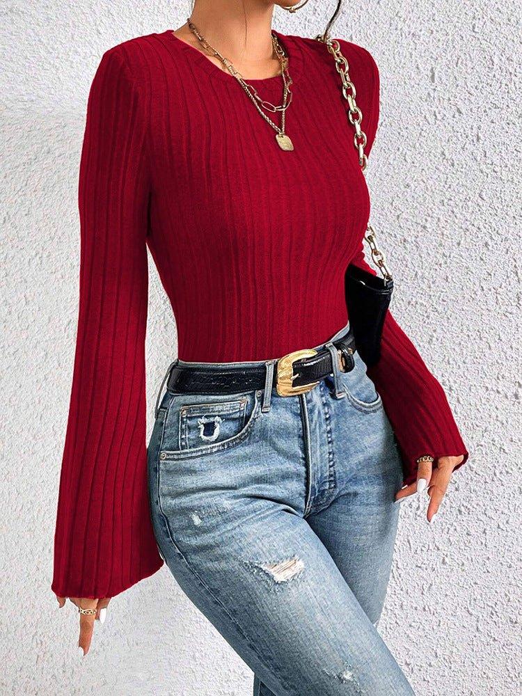 Close-up of a woman's torso wearing a red ribbed knit top with flared sleeves.