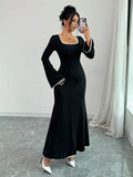 Woman taking a selfie in a black maxi dress with white contrast piping and bell sleeves.