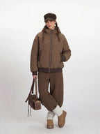 Model posing in a brown quilted bomber jacket and matching brown trousers.