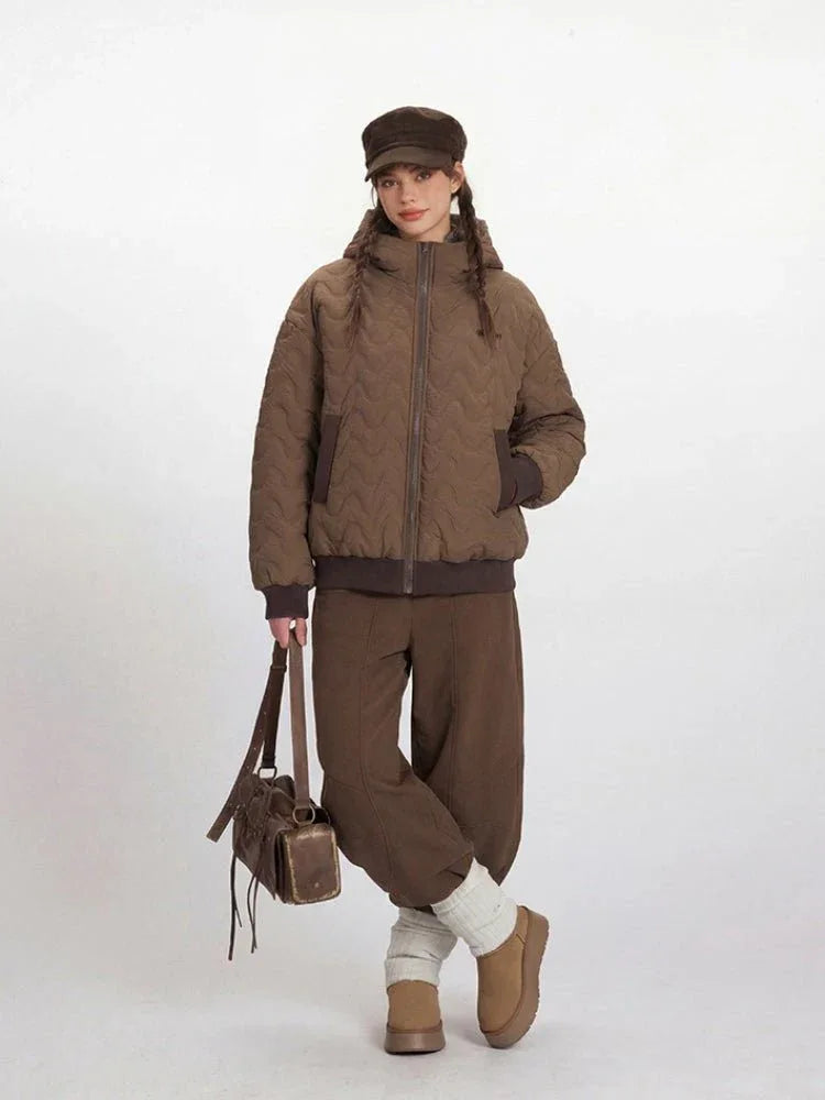 Model posing in a brown quilted bomber jacket and matching brown trousers.