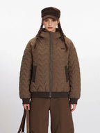 Front view of a woman in a brown quilted bomber jacket with a zipper and side pockets.