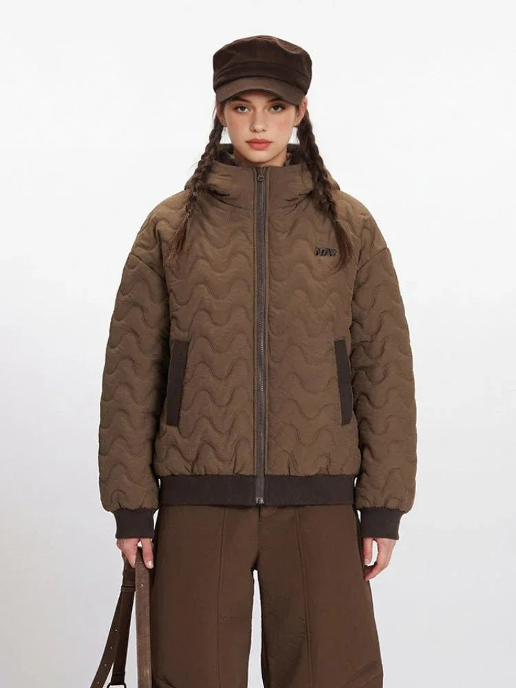 Front view of a woman in a brown quilted bomber jacket with a zipper and side pockets.