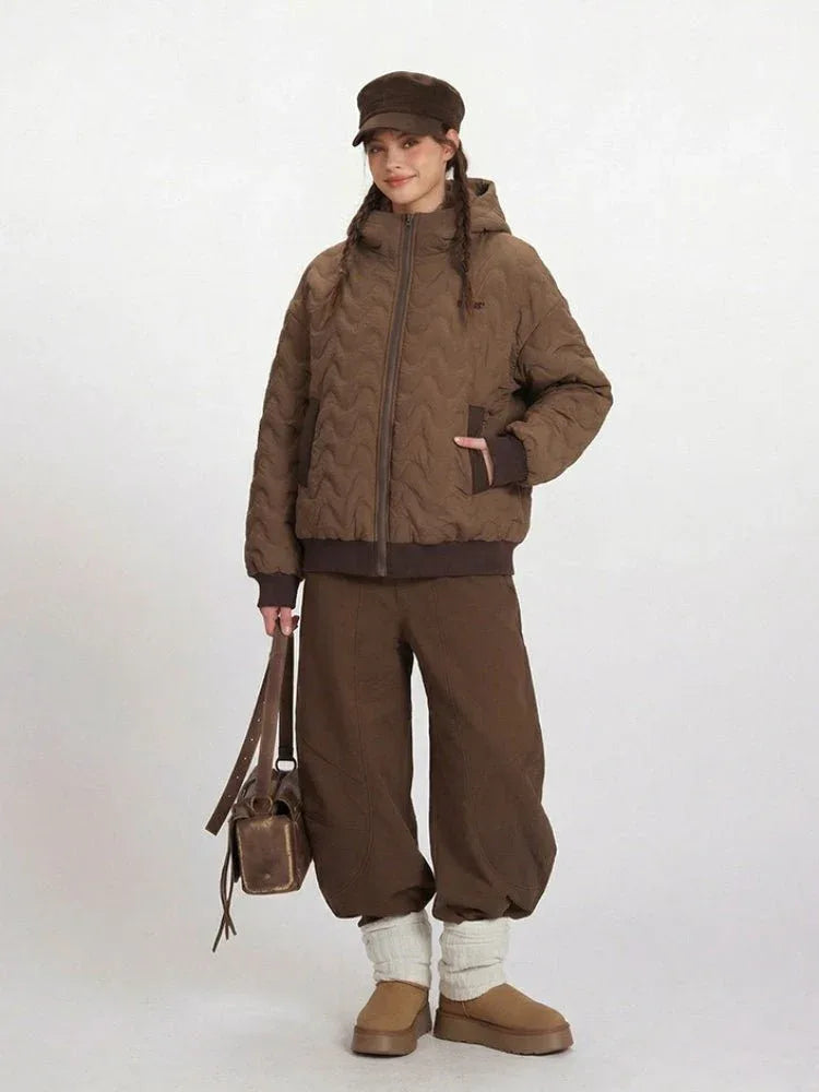 Full-length shot of a woman in a brown quilted bomber jacket and wide-leg brown pants.