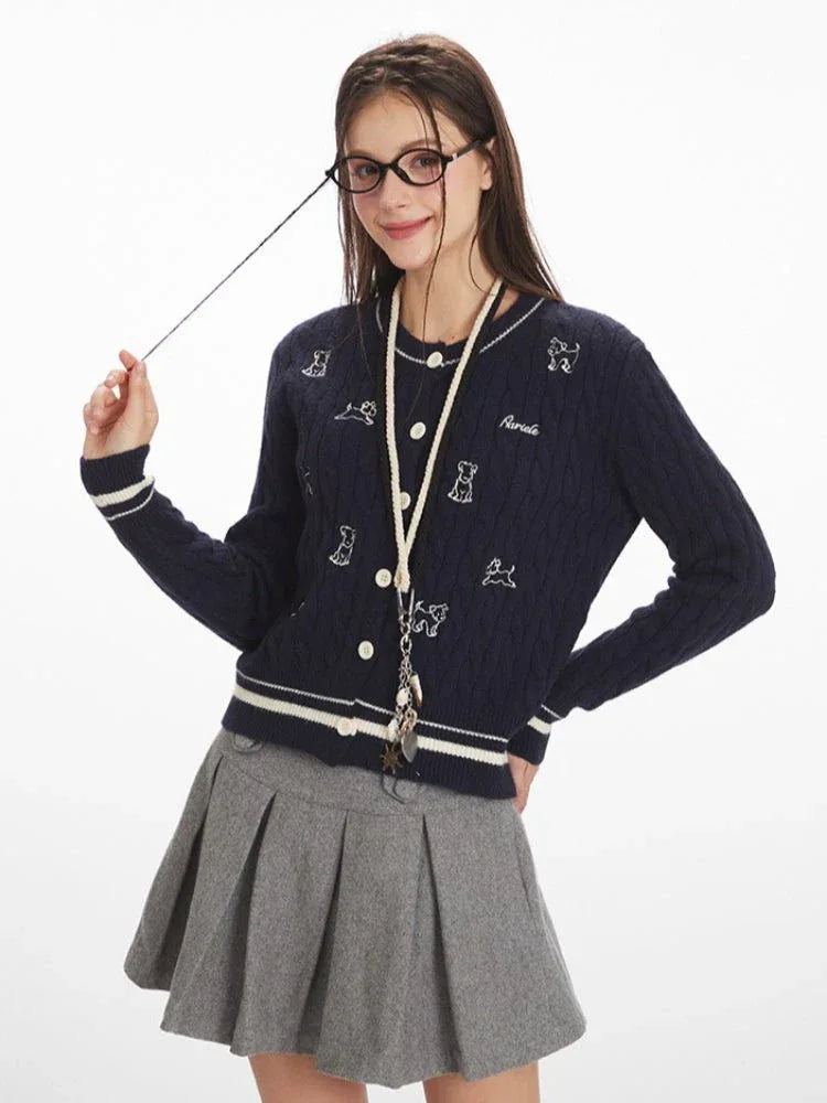 Woman in a navy blue cable knit cardigan with embroidered dog pattern, adjusting glasses