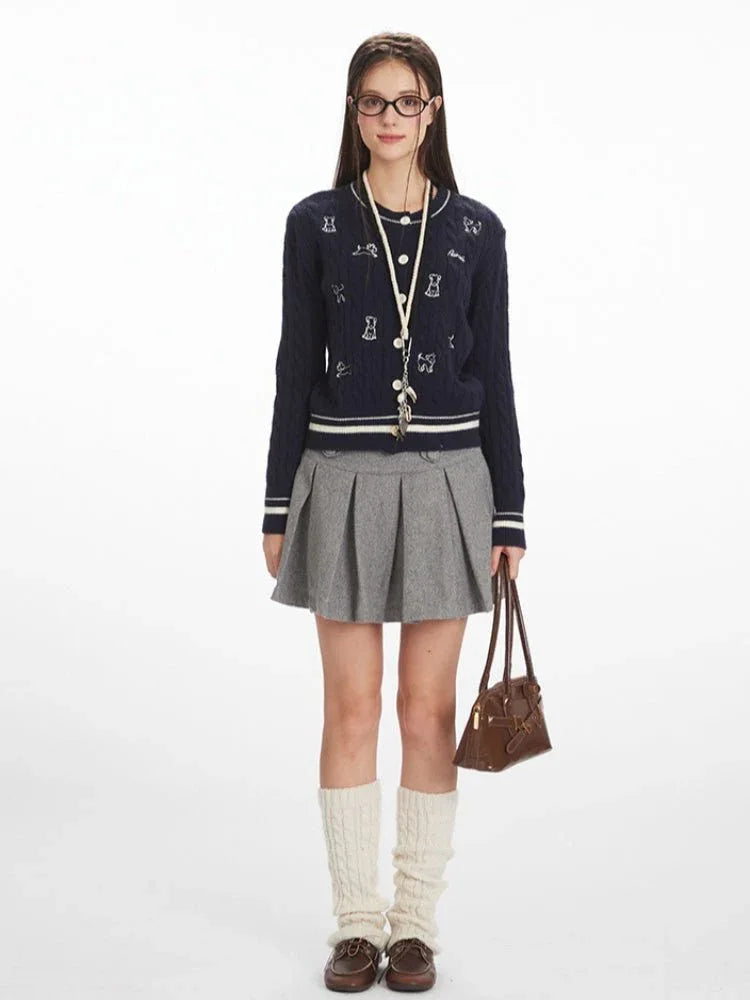 Woman wearing a navy blue cable knit cardigan with embroidered dog pattern and white stripe trim