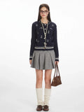 Woman wearing a navy blue cable knit cardigan with embroidered dog pattern and white stripe trim