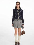 Woman wearing a navy blue cable knit cardigan with embroidered dog pattern and white stripe trim