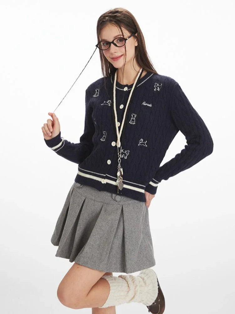 Woman in a navy blue cable knit cardigan with embroidered dog pattern, posing playfully