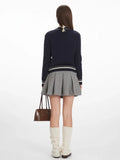 Back view of a woman in a navy blue cable knit cardigan with embroidered dog pattern