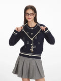 Woman in a navy blue cable knit cardigan with embroidered dog pattern, holding the neckline cord