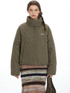Close-up of the green puffer jacket, highlighting the quilted texture and funnel neck.