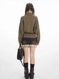Back view of a woman wearing a green graphic print sweatshirt with a collared button placket, black denim skirt with fur trim, and black boots.