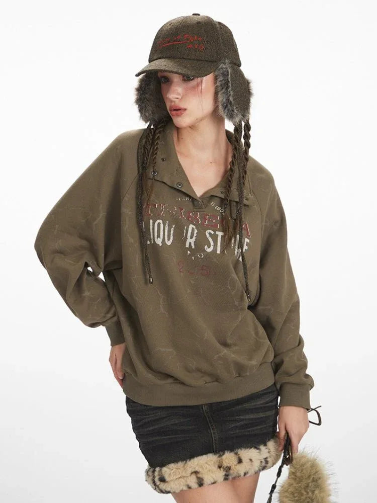 Close-up of a woman wearing a green graphic print sweatshirt with a collared button placket and black denim skirt with fur trim.