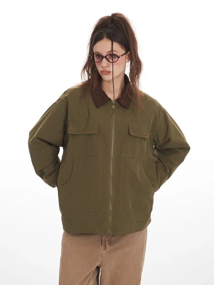 Front view of a woman wearing an olive green jacket with a brown collar, featuring dual chest pockets and front zipper closure.