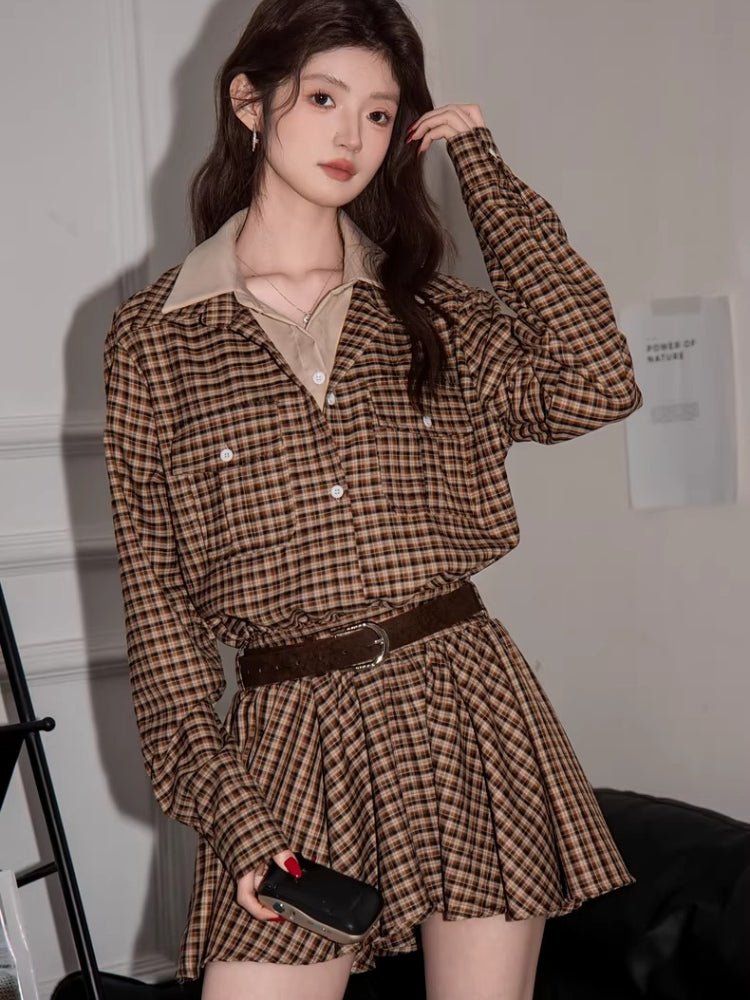 Woman holding a phone while wearing the brown plaid shirt dress