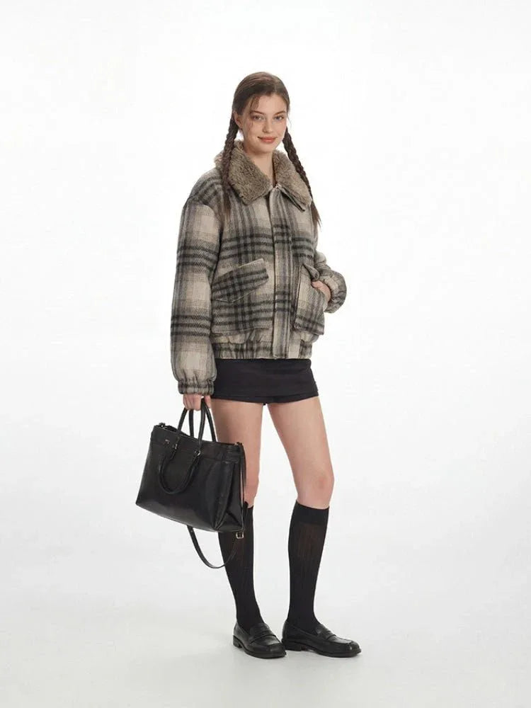 Side view of a woman in a plaid bomber jacket with a fur collar, holding a black handbag.